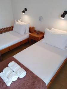 2 łóżka w pokoju z białą pościelą i poduszkami w obiekcie Loggia w mieście Agia Galini