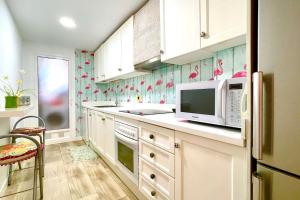uma cozinha com armários brancos e pássaros cor-de-rosa na parede em 12-Apartamento en la playa Piscina em Alicante