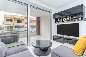 uma sala de estar com uma televisão, um sofá e uma mesa em Mirage 2-BR Apartment in Larnaca em Lárnaca
