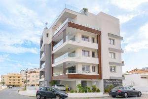 拉納卡的住宿－Mirage 2-BR Apartment in Larnaca，一座白色的建筑,前面有汽车停放