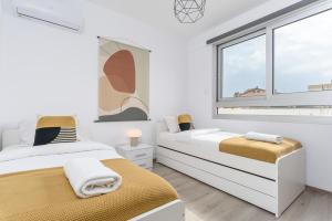a white bedroom with two beds and a window at Mirage 2-BR Apartment in Larnaca in Larnaca