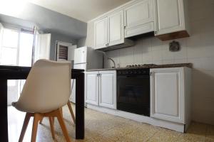 MistrettaにあるExclusive Apartments in centerのキッチン(白いキャビネット、椅子、コンロ付)