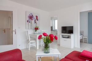 een woonkamer met een vaas met rode bloemen op een tafel bij Duen12_36 in Westerland