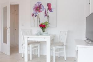een witte tafel met twee stoelen en een vaas met bloemen bij Duen12_36 in Westerland