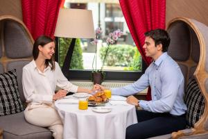 a man and woman sitting at a table with a plate of food at Aria Hotel Budapest by Library Hotel Collection in Budapest