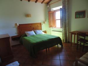 een slaapkamer met een groen bed, een tafel en een raam bij LaSelva in Albinia
