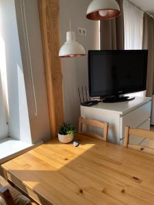 uma sala de estar com uma mesa de madeira e uma televisão de ecrã plano em Mājīgs studio apartaments jūras pilsētā em Ventspils