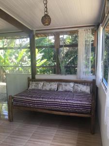 a bed sitting in a room with windows at Casa especial em Itacaré in Itacaré