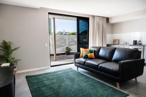 a living room with a black leather couch and a green rug at 107 George in Kalbar