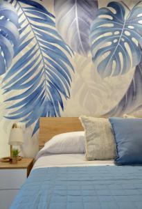 um quarto com uma cama azul e um mural de folhas em TraMonti Apartments Pescara em Pescara