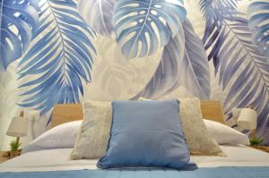 1 dormitorio con 1 cama con un mural de hojas de palmera en TraMonti Apartments Pescara, en Pescara