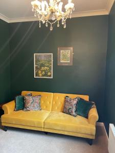 a yellow couch in a living room with a chandelier at The Lodge at Salhouse in Norwich