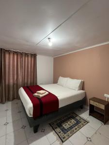 um quarto com uma cama com um cobertor vermelho e branco em Ckoinatur Hostel em San Pedro de Atacama