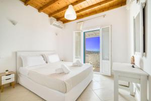 Lofos Apartments في بلاتيس يالوس ميكونوس: غرفة نوم بيضاء مع سرير وشرفة