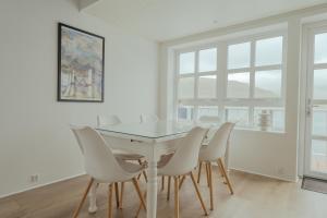 een eetkamer met een glazen tafel en witte stoelen bij Dahlastova / Stunning Boathouse / Bay View / 3BR in Hvalvík