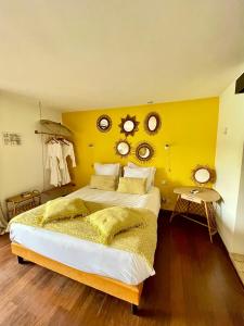 ein Schlafzimmer mit einem großen Bett mit gelber Wand in der Unterkunft O Petit Monde in Sanary-sur-Mer
