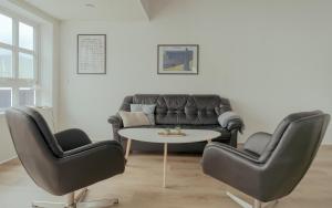 een woonkamer met een bank, 2 stoelen en een tafel bij Dahlastova / Stunning Boathouse / Bay View / 3BR in Hvalvík