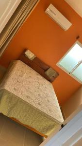 ein kleines Bett in einem Zimmer mit orangefarbener Wand in der Unterkunft HOTEL RANCHO EL NOVATO in Concepción de La Vega