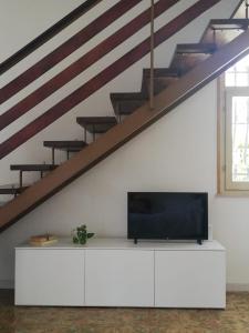 チェゼナーティコにあるCasa Cesenaticoの階段下の白いキャビネットに座るテレビ