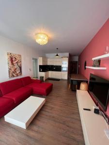 Hard Rock Apartments في سارنده: غرفة معيشة مع أريكة حمراء وتلفزيون