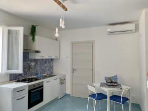 - une cuisine avec des placards blancs, une table et des chaises dans l'établissement le calette Marettimo, à Marettimo