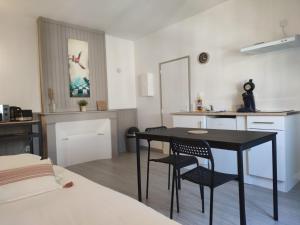 a bedroom with a table and chairs and a kitchen at *LES STUDIOS L'AMANDINE* in Périgueux