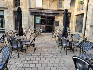an outdoor patio with tables and chairs and umbrellas at *LES STUDIOS L'AMANDINE* in Périgueux