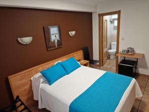 ein Schlafzimmer mit einem Bett mit blauen Kissen und einem Badezimmer in der Unterkunft Hostería VISTAPARK in El Astillero