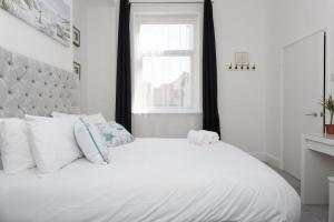 a white bed with white pillows and a window at Dockyard Dreams in Portsmouth