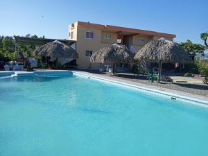 ein Pool mit Strohschirmen und ein Gebäude in der Unterkunft HOTEL RANCHO EL NOVATO in Concepción de La Vega