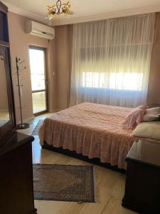 a bedroom with a bed and a large window at شقة مفروشة للايجار في عمان شارع الجامعة الاردنية in Amman