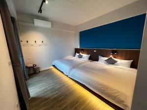 1 dormitorio con 2 camas y pared azul en 漁聲民宿 FishON B&B, en Magong