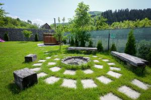 a garden with benches and a fire pit in the grass at Chalet Bora in Vişeu de Jos