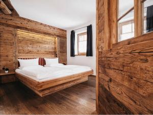 a bed in a room with a wooden wall at Almwellness-Resort Tuffbad in Sankt Lorenzen im Lesachtal