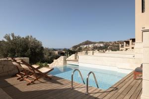 a pool with a wooden deck and a chair next to it at Paralos Irini Mare in Agia Galini