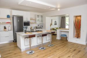 a kitchen with white cabinets and a kitchen island with bar stools at Sunset Farm Stellenbosch in Stellenbosch