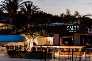 un ristorante con tavoli, sedie e un albero di Cavo Zoe Seaside Hotel a Protaras