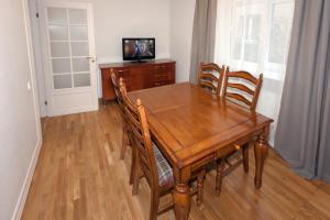 a wooden dining room table with chairs and a television at Vytauto apartamentai in Palanga