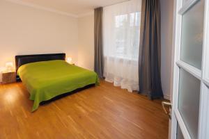 Un dormitorio con una cama verde y una ventana en Vytauto apartamentai, en Palanga