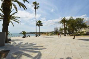a person walking down a sidewalk with palm trees at Apartamentos Turisticos Lindomar in Armação de Pêra