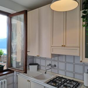 a kitchen with white cabinets and a sink and a window at La casa di Guia in Perledo