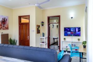 a living room with a blue couch and a tv at City Gem by Havana Properties near the French Embassy, Tanzanite Bridge & Coco Beach in Dar es Salaam
