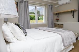 a bedroom with a white bed and a window at Sunset Farm Stellenbosch in Stellenbosch
