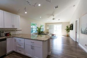 una cucina con armadietti bianchi e pavimenti in legno massello di New Construction - Pristine Home - Great Location a Stuart