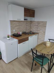 eine Küche mit weißen Schränken, einem Tisch und einem Waschbecken in der Unterkunft Apartmani Kuljanin in Donji Milanovac