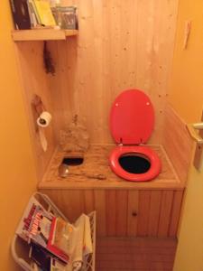 ein WC mit rotem Sitz in einem hölzernen Badezimmer in der Unterkunft Maison Lama 