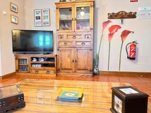 una sala de estar con TV y una cabaña de madera en Apartamento El Rey, en Colombres