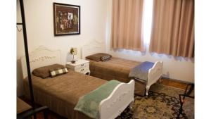 a bedroom with two beds and a table and a mirror at Apto Confortável e Completo em São Pelegrino 22 in Caxias do Sul