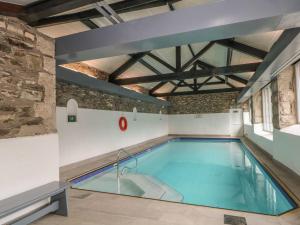 a swimming pool in a building with a brick wall at Can Brow in Rusland