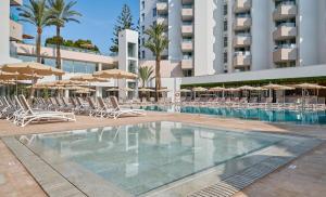 a swimming pool with lounge chairs and umbrellas at Hipotels Bahía Grande Aparthotel in Cala Millor